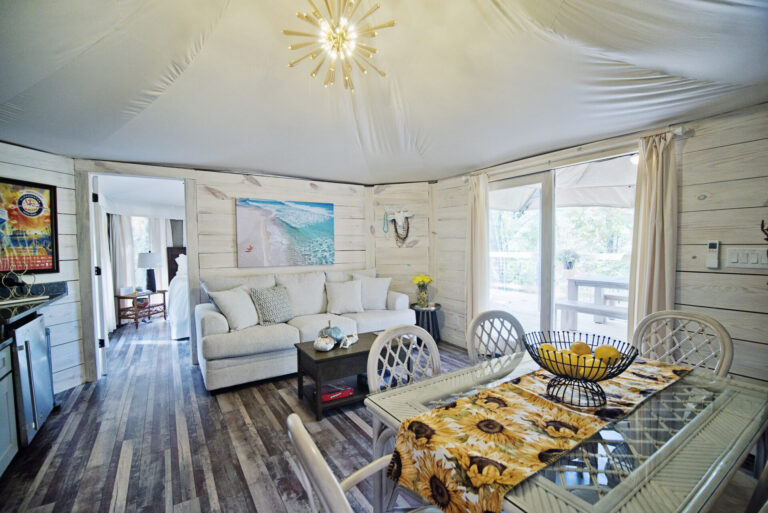 A bright white room inside a clamping tent with a couch and nautical themed decor at The Destination glamping at Lake Martin